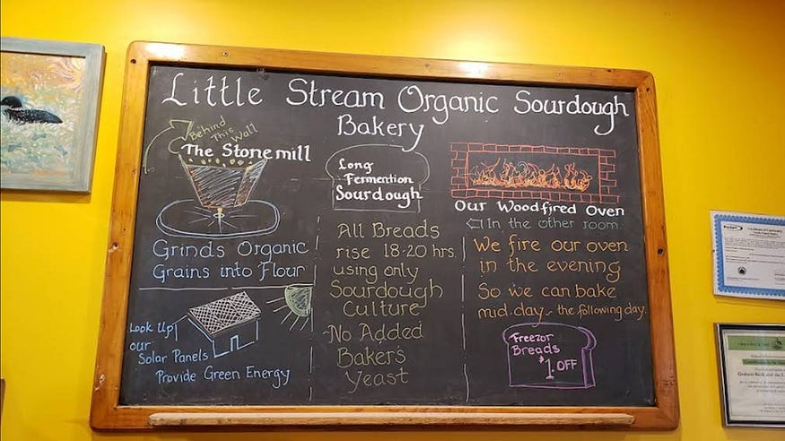 A bakery chalkboard hanging on a mustard-yellow wall. A bakery chalkboard hanging on a mustard-yellow wall.