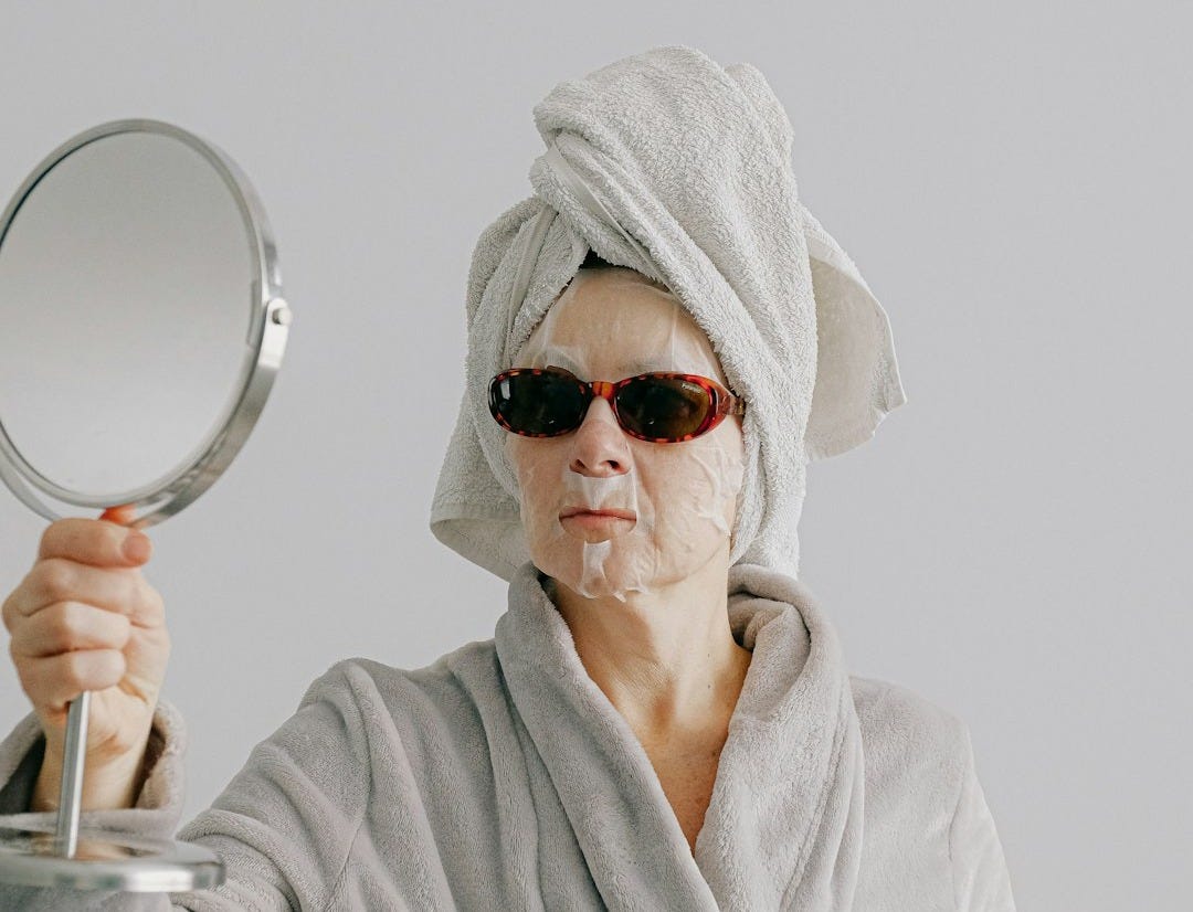 a woman with a towel on her head holding a mirror