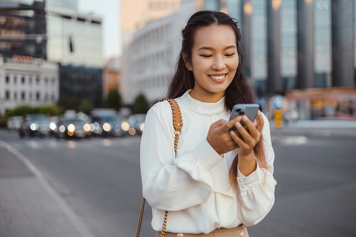woman using a smartphone on a sidewalk woman using a smartphone on a sidewalk