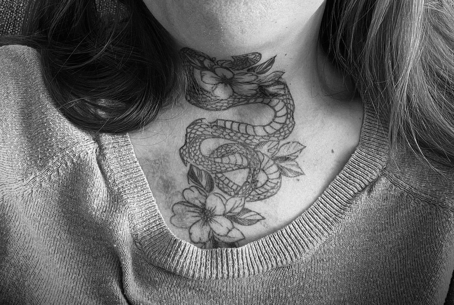 A cropped black-and-white photo of my neck tattoo, a glorious snake with flowers