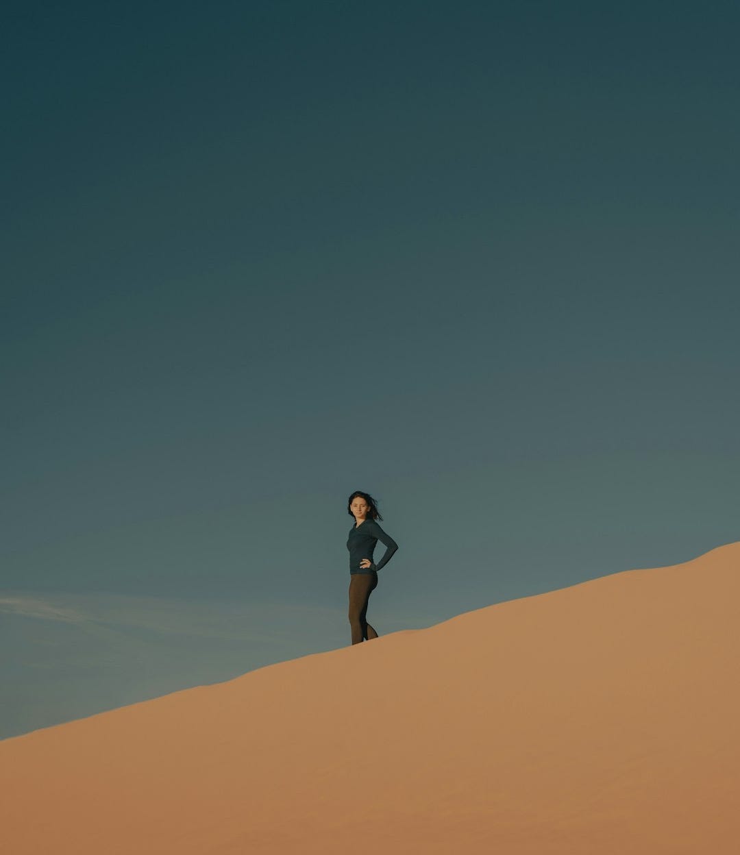 woman in black shirt and black shorts standing on brown sand during daytime