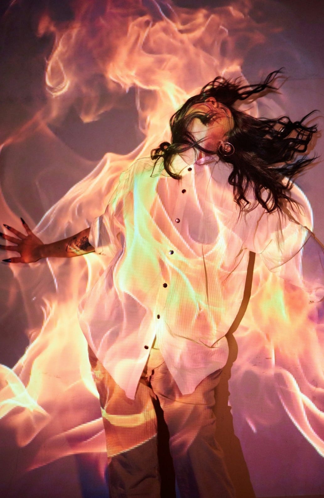 A woman in a white shirt is dancing with fire