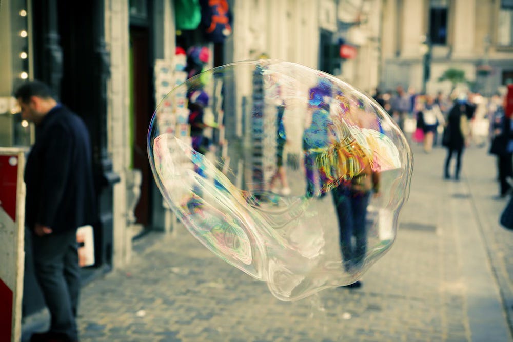A street scene with a bubble partially obscuring a person walking toward the camera so it looks like they are inside it