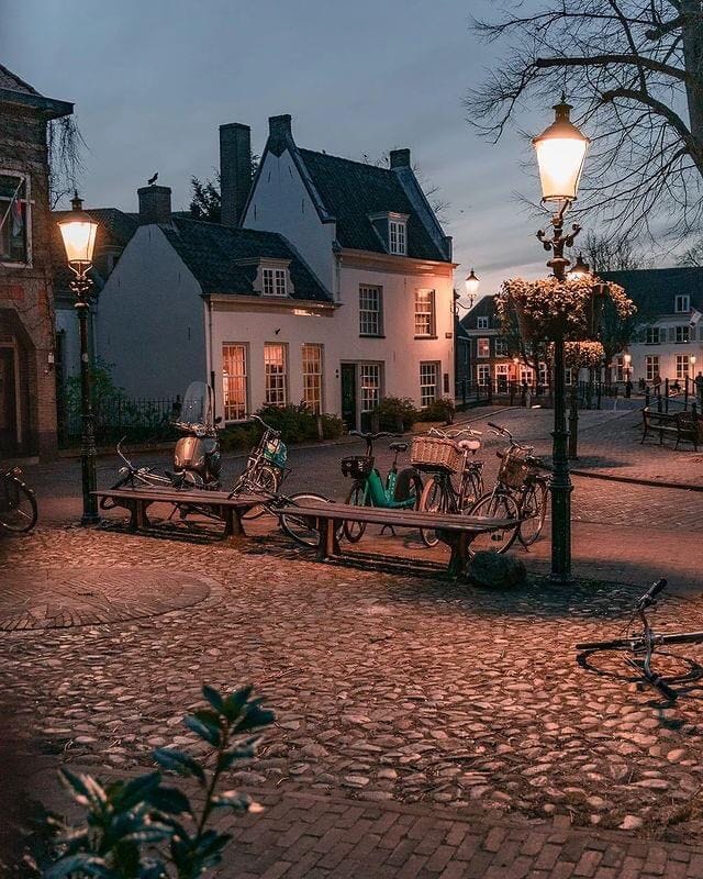 This may contain: several bicycles are parked on benches in front of a building at night with street lights