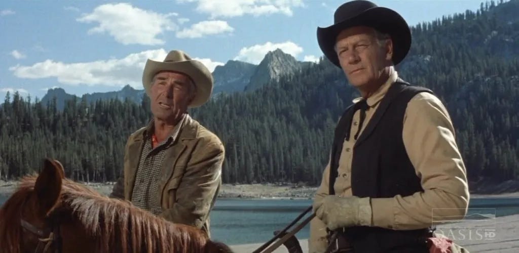Randolph Scott and Joel McCrea sit on horseback against the backdrop of a California pine forest. A screenshot from Ride the High Country (1962).