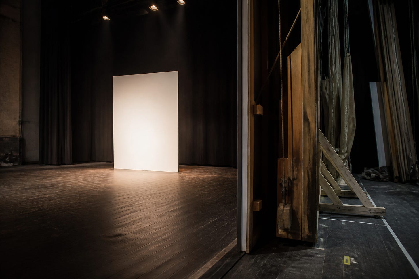 Scenă minimalistă luminată, cu structurile și mecanismele din culise vizibile lateral Scenă minimalistă luminată, cu structurile și mecanismele din culise vizibile lateral