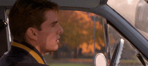 a man sitting in a car with a yellow and black sweater on