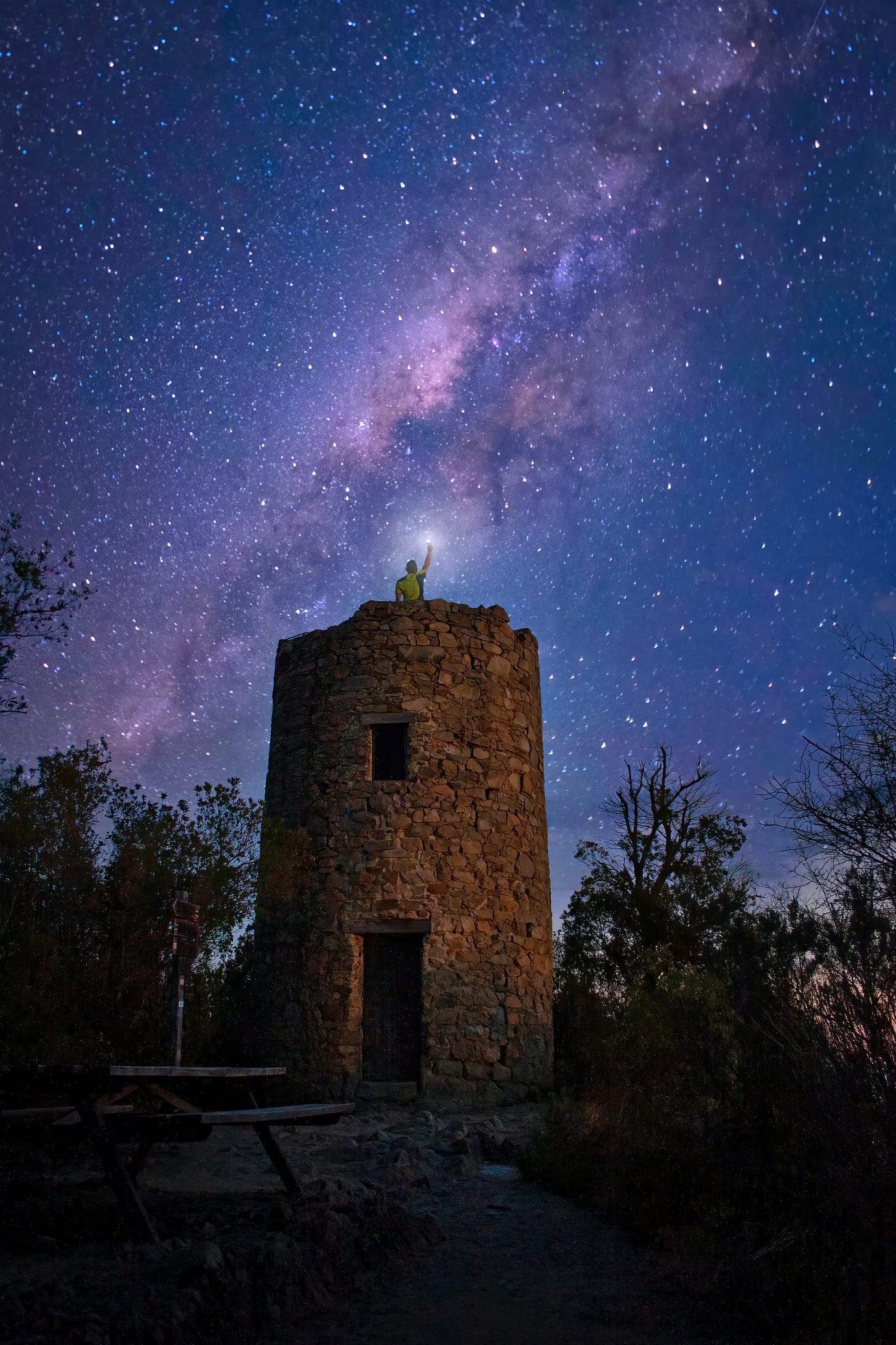 A stone tower with a person or statue on top reaching toward the starry sky A stone tower with a person or statue on top reaching toward the starry sky