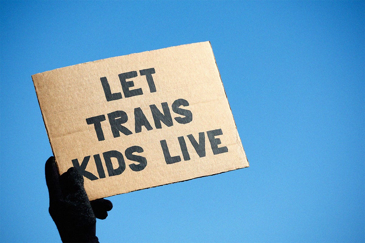 A transgender rights supporter takes part in a rally outside of the U.S. Supreme Court as the high court hears arguments in a case on transgender health rights on December 04, 2024 in Washington, DC. They hold a sign that reads "Let Trans Kids Live".