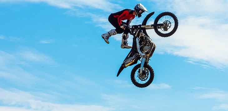 Photo of a man on a motorcycle leaping into the ar.