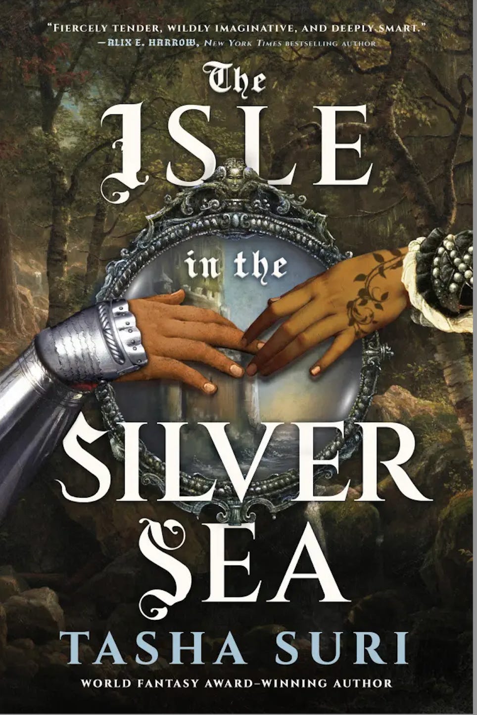 cover of Tasha Suri Isle in the Silver Sea; shows a forest in background; in foreground two brown women's hands, one in a knight's glove, one in a green sleeve with ferns circling it, are reaching to touch each other across a circular brooch/window in which is a castle