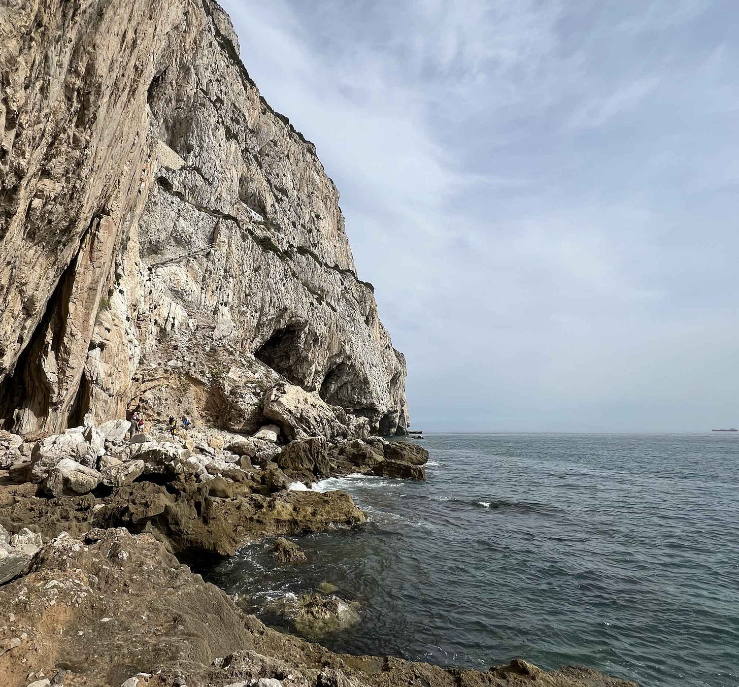 View of Vanguard Cave at the base of the Rock cliff face with sea at right View of Vanguard Cave at the base of the Rock cliff face with sea at right