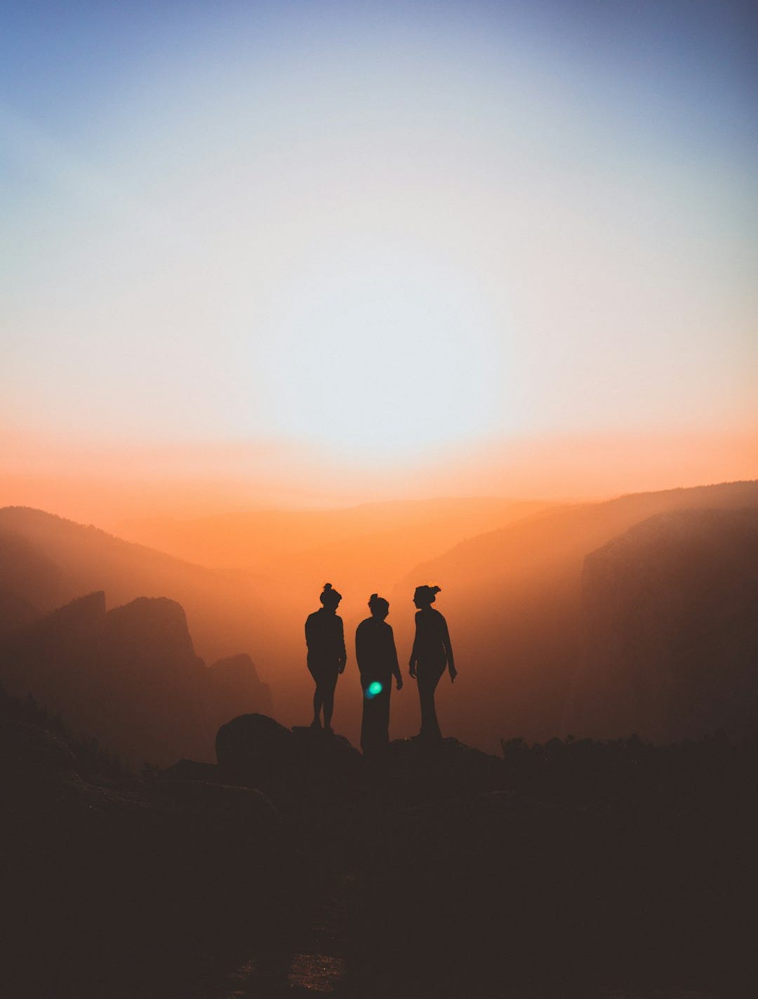 silhouette of three people up on mountain cliff silhouette of three people up on mountain cliff