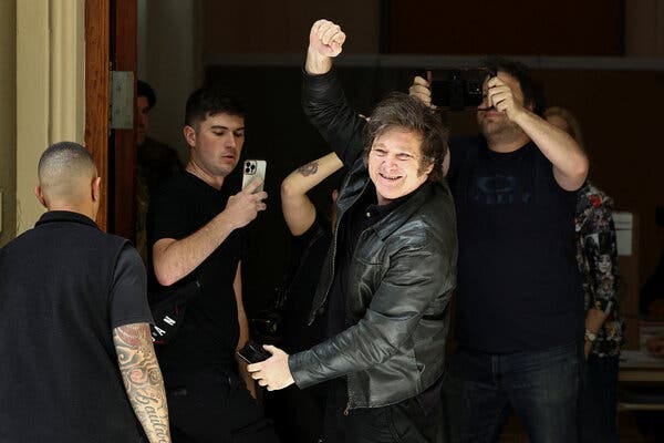 An Argentine presidential candidate campaigning in a dark jacket as people take photos. An Argentine presidential candidate campaigning in a dark jacket as people take photos.