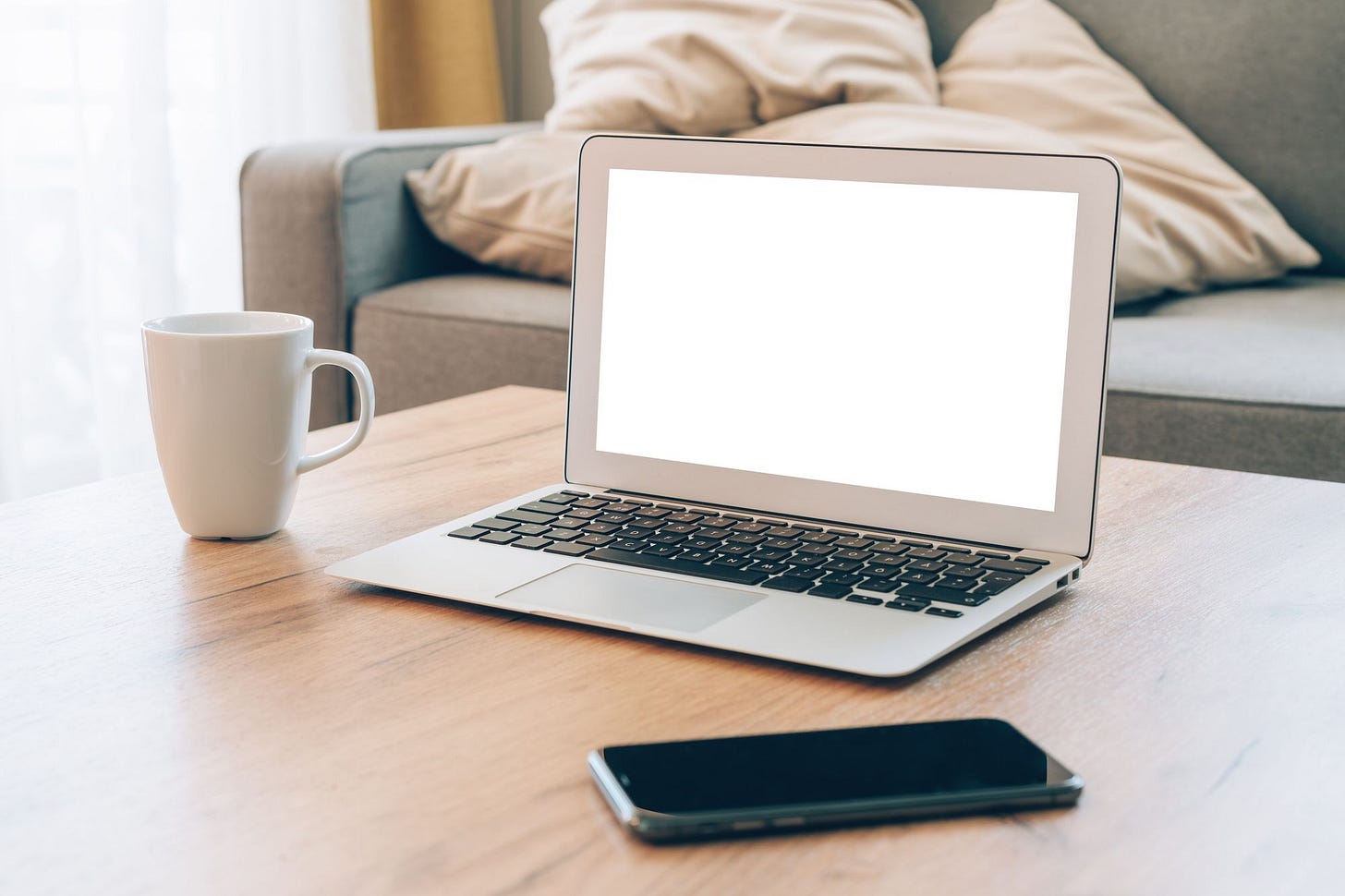 Laptop with screen on, phone, and a mug on the table Laptop with screen on, phone, and a mug on the table