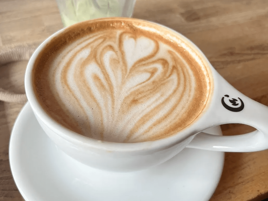 A hot latte in a white ceramic mug with heart-shaped latte art from Commonplace coffee