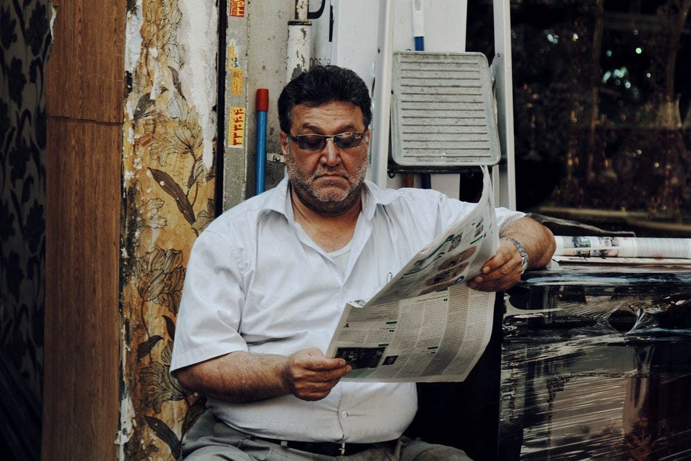 man in white polo shirt reading newspaper man in white polo shirt reading newspaper