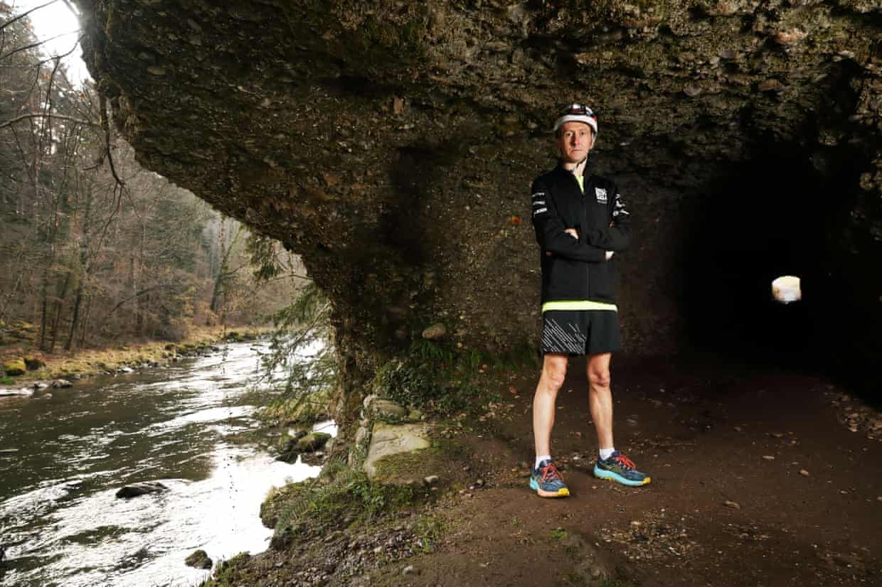James Mason, who won the world's deepest marathon, in running gear next to a river, with rocks behind him, in Switzerland