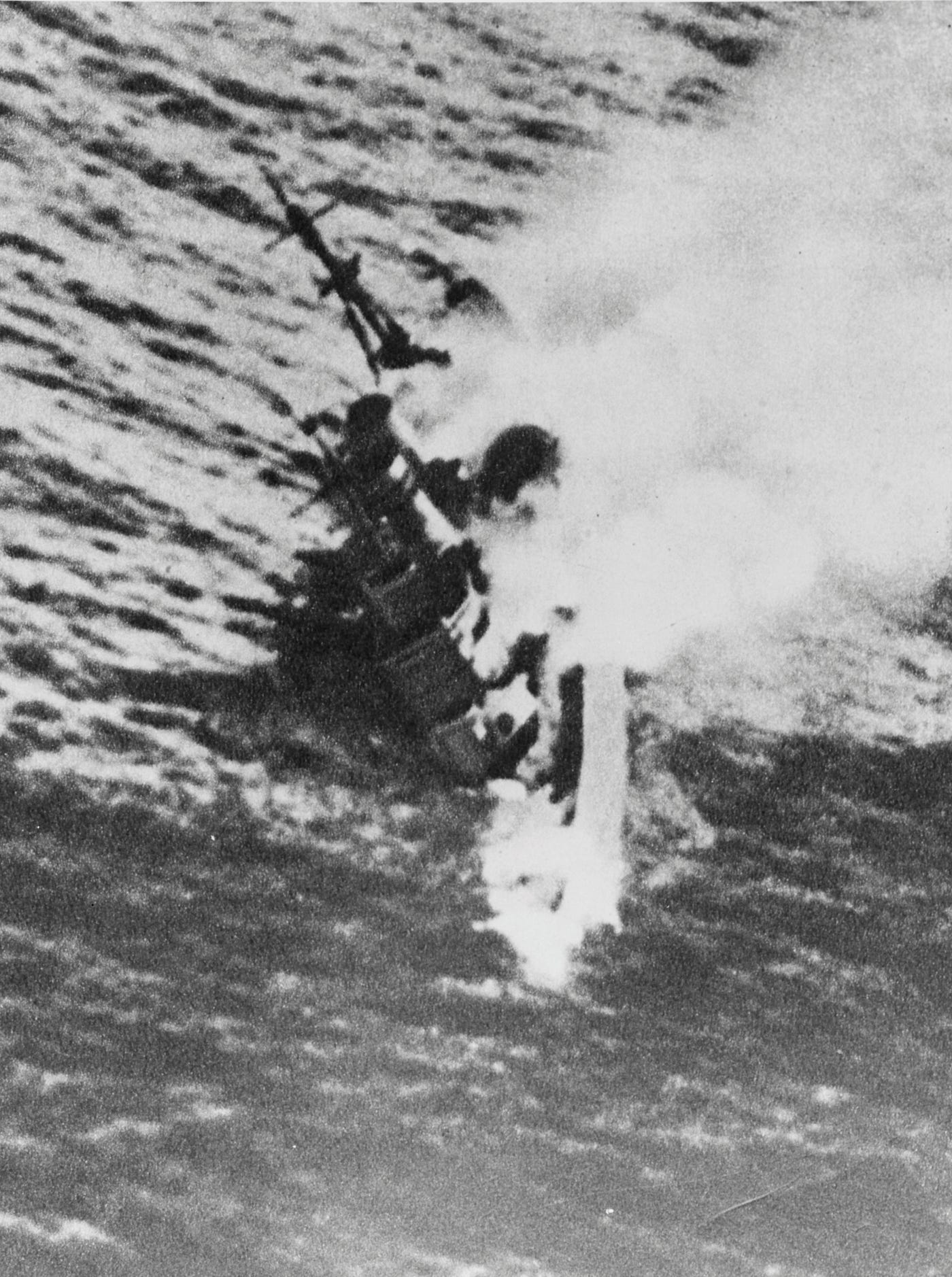 A close up photo showing H.M.S. Exter sinking during the Second Battle of the Java sea. The ship nose is disappearing beneath the surface as smokes billows out of its hull. A close up photo showing H.M.S. Exter sinking during the Second Battle of the Java sea. The ship nose is disappearing beneath the surface as smokes billows out of its hull.