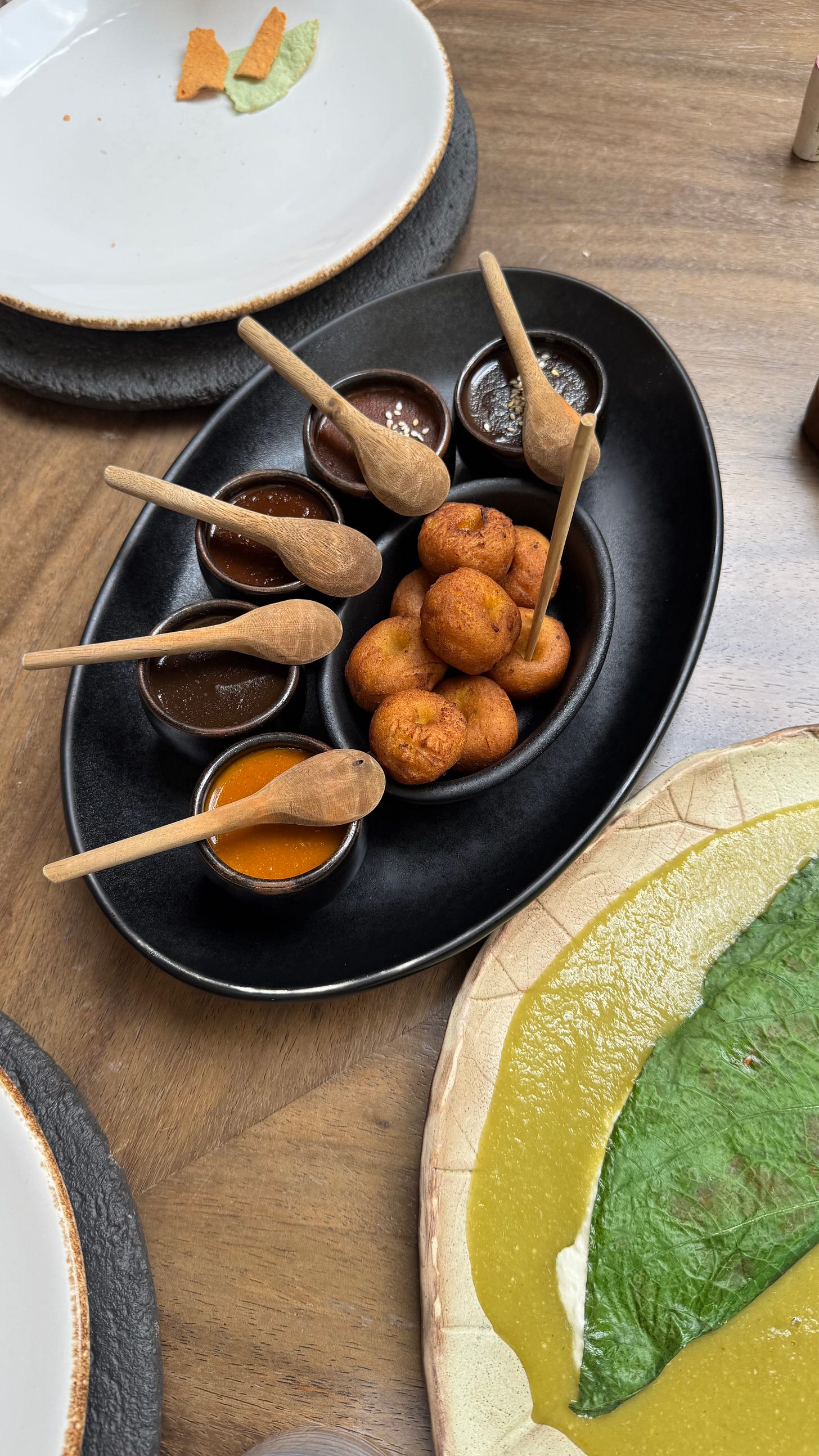 Five types of mole in small ceramic bowls with a pile of chochoyote dumplings.