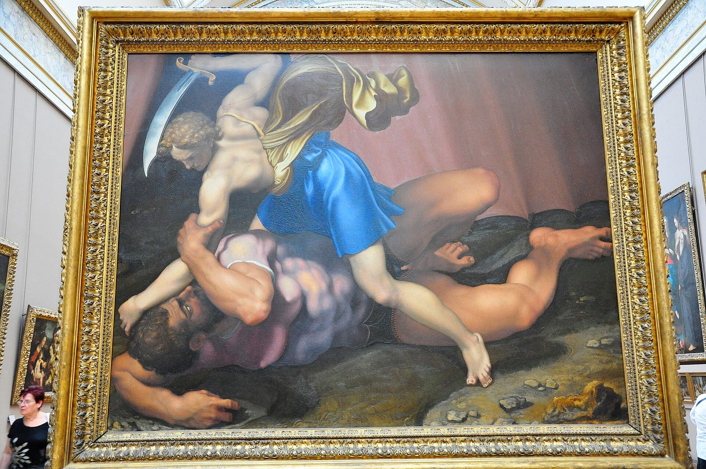 David, sword raised, kneels on the back of the fallen giant Goliath and pins him to the ground. David, sword raised, kneels on the back of the fallen giant Goliath and pins him to the ground.