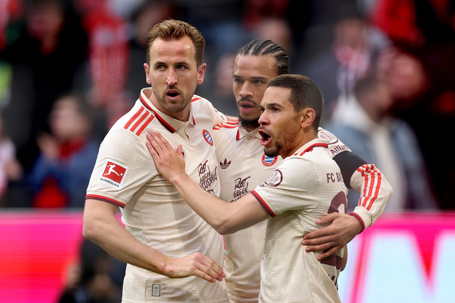Harry Kane embraces Leroy Sane and Raphael Guerreiro after Bayern goal.