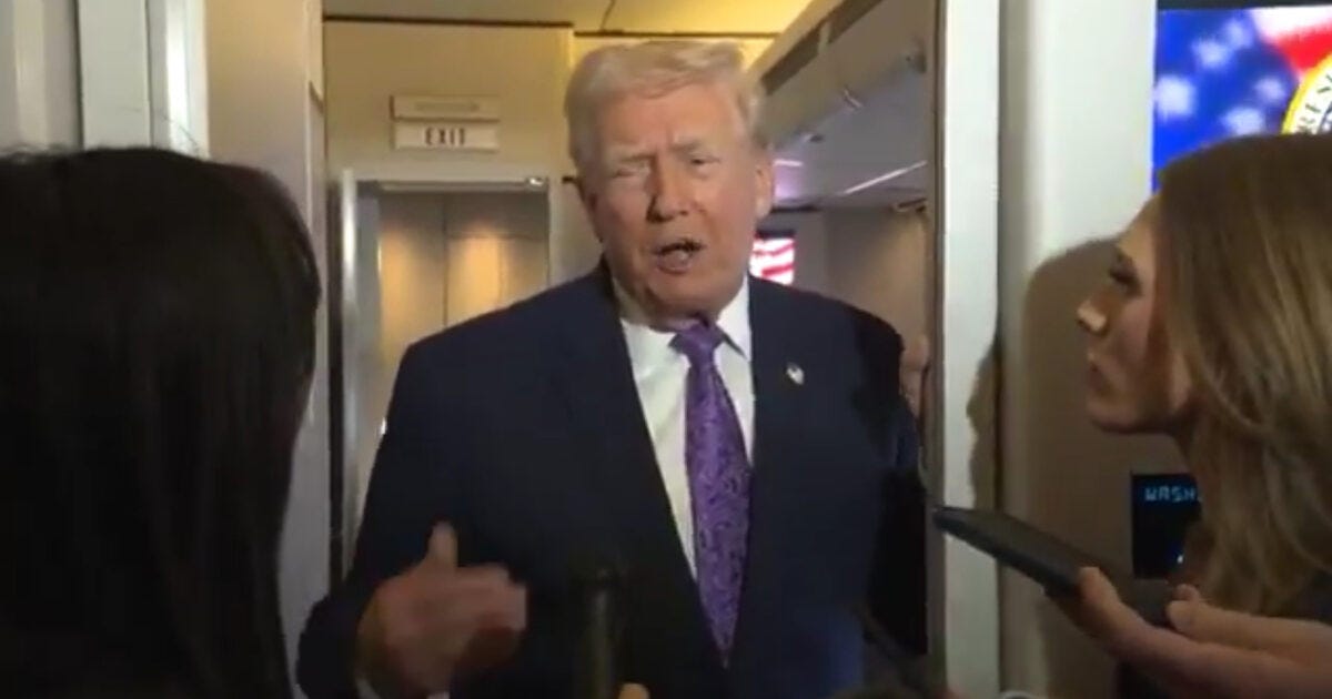 Former President Donald Trump speaks to reporters in a narrow hallway, surrounded by journalists during a press event.