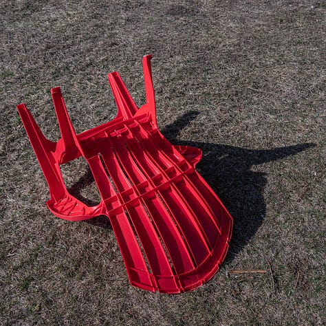 A 2 x 3 grid of six photographs with red things: a round red circle above a hard beam, an upside down red plastic chair, leaves from a red Japanese maple, a red watering, a red Radio Flyer tricycle and a bowl of red rotting watermelon 