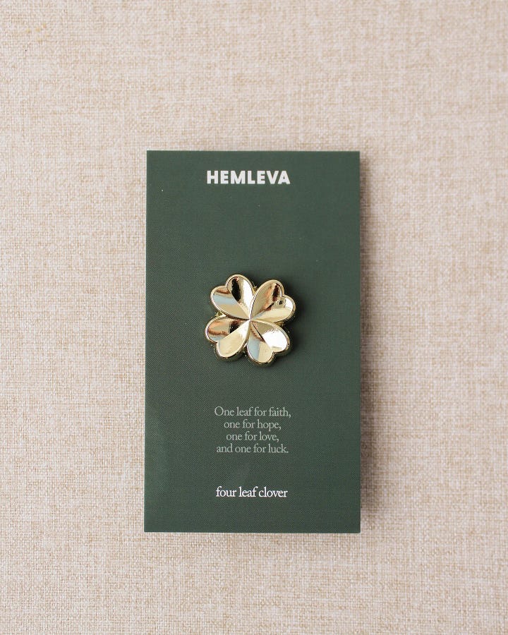 First Photo: a set of  handmade, rounded, teal and pink, ceramic salt and pepper shakers by E Lo Ceramic Arts.  Second photo: a gold plated four leaf clover pin by HEMLEVA