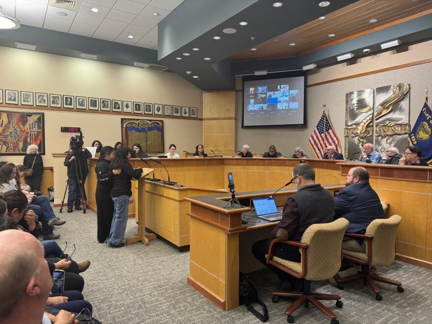 A young girl speaking publicly at a podium in front of a city council.