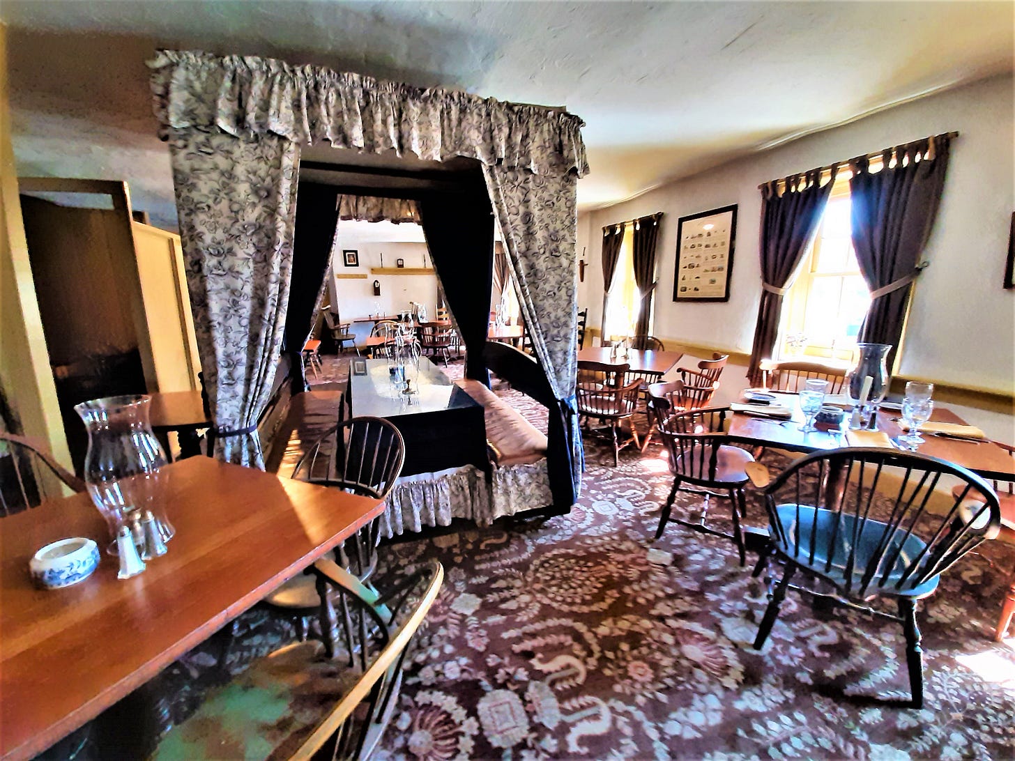 Tester bed style dining at the Dobbin House with other dining tables. light shining through windows.