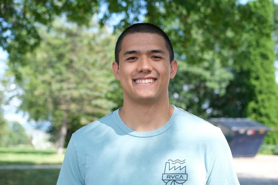 Jake smiles at the camera with trees in the background
