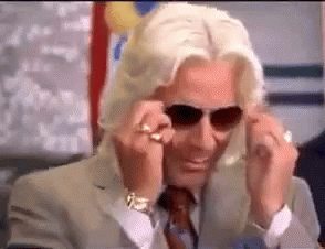 a man in a suit and tie is wearing sunglasses and a ring .