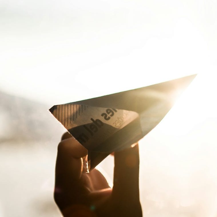 person holding paper plane person holding paper plane