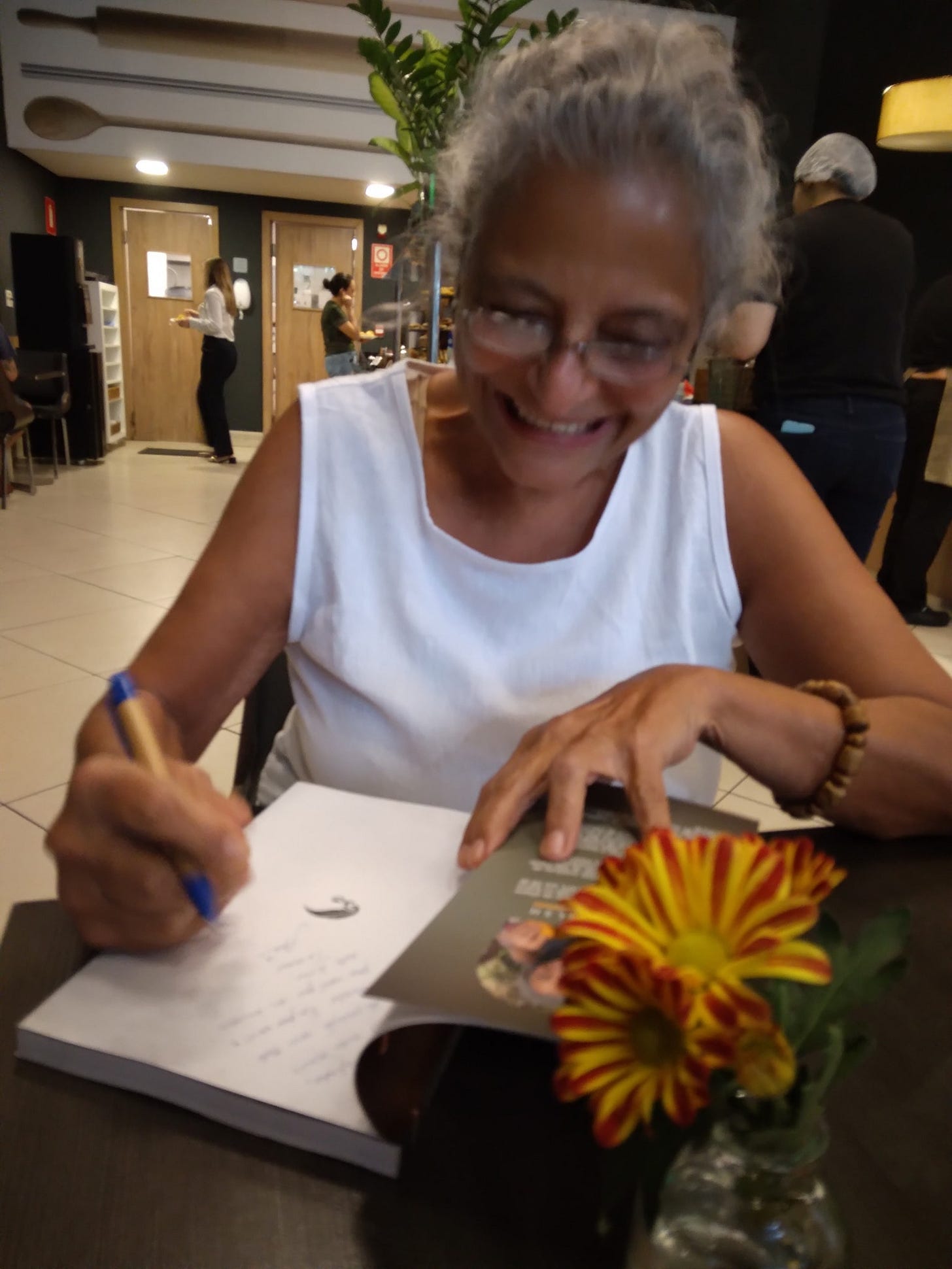 Ane Walsh smiling as she signs a copy of her book Notas da Perfumista