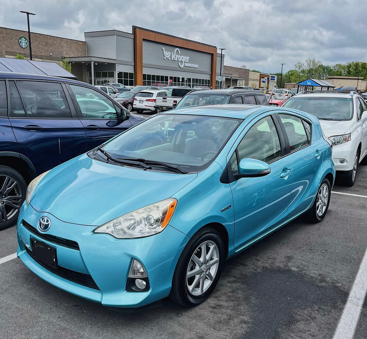 A light blue Toyota Prius parked in a grocery store parking lot