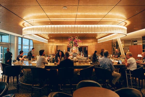 Guests sit around a bar with a gleaming light illuminating the area. 