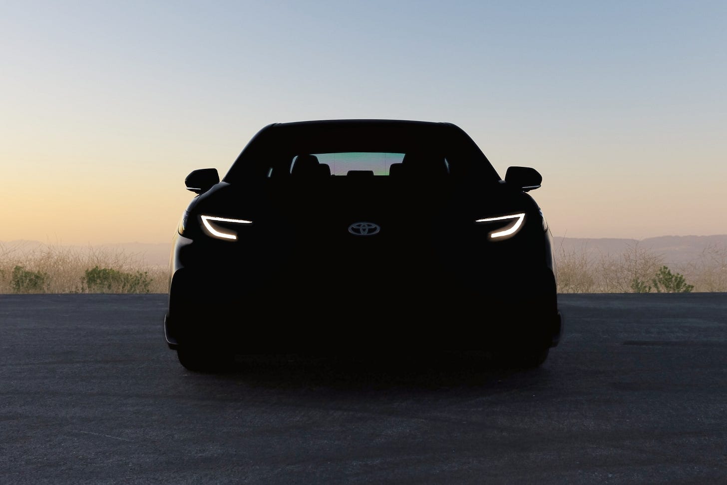 A dark car parked at sunset is likely the redesigned 2025 Toyota Camry.