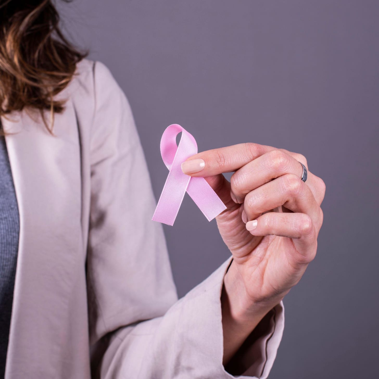 Cropped image of woman holding a pink badge ribbon to support breast cancer Cropped image of woman holding a pink badge ribbon to support breast cancer