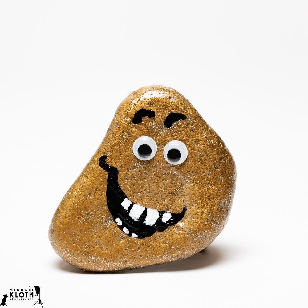 A gold rock 'monster' with two googly eyes photographed with a white studio background. A gold rock 'monster' with two googly eyes photographed with a white studio background.