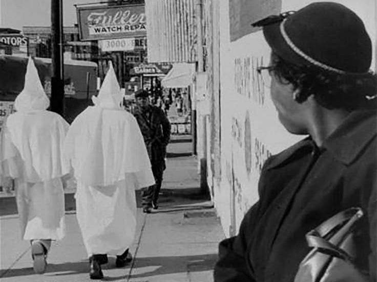 This may contain: three people in ghost costumes walking down the street