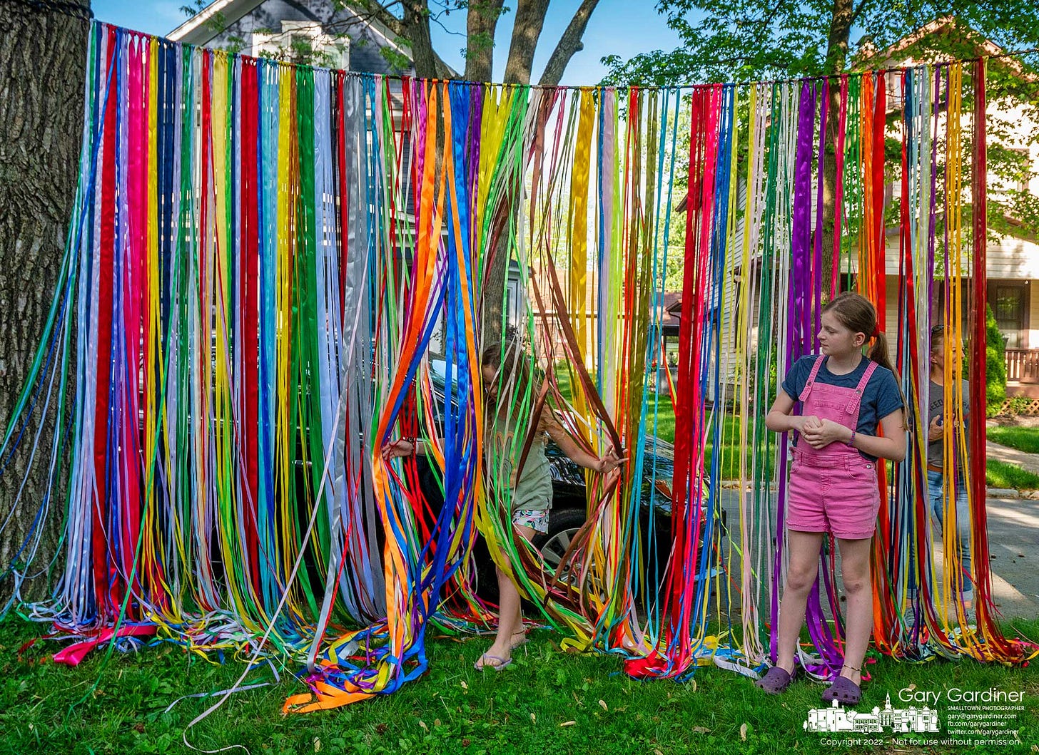 A young girl runs through a curtain of colored ribbons hanging between trees at the Vine Street Art Walk in Uptown Westerville Sunday evening. My Final Photo for May 15, 2022. A young girl runs through a curtain of colored ribbons hanging between trees at the Vine Street Art Walk in Uptown Westerville Sunday evening. My Final Photo for May 15, 2022.