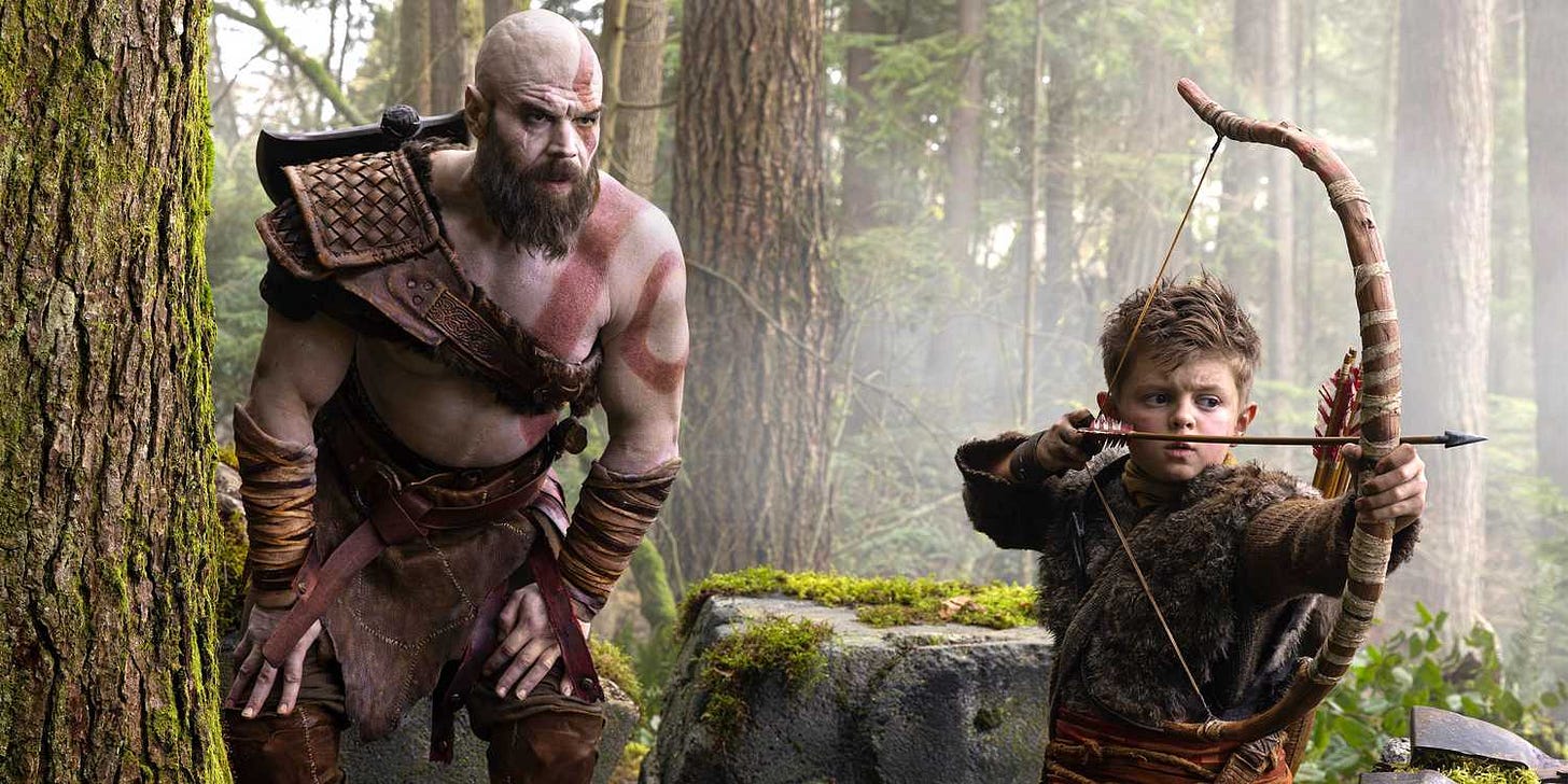 Kratos leaning over Atreus drawing a bow in God of War. Kratos leaning over Atreus drawing a bow in God of War.