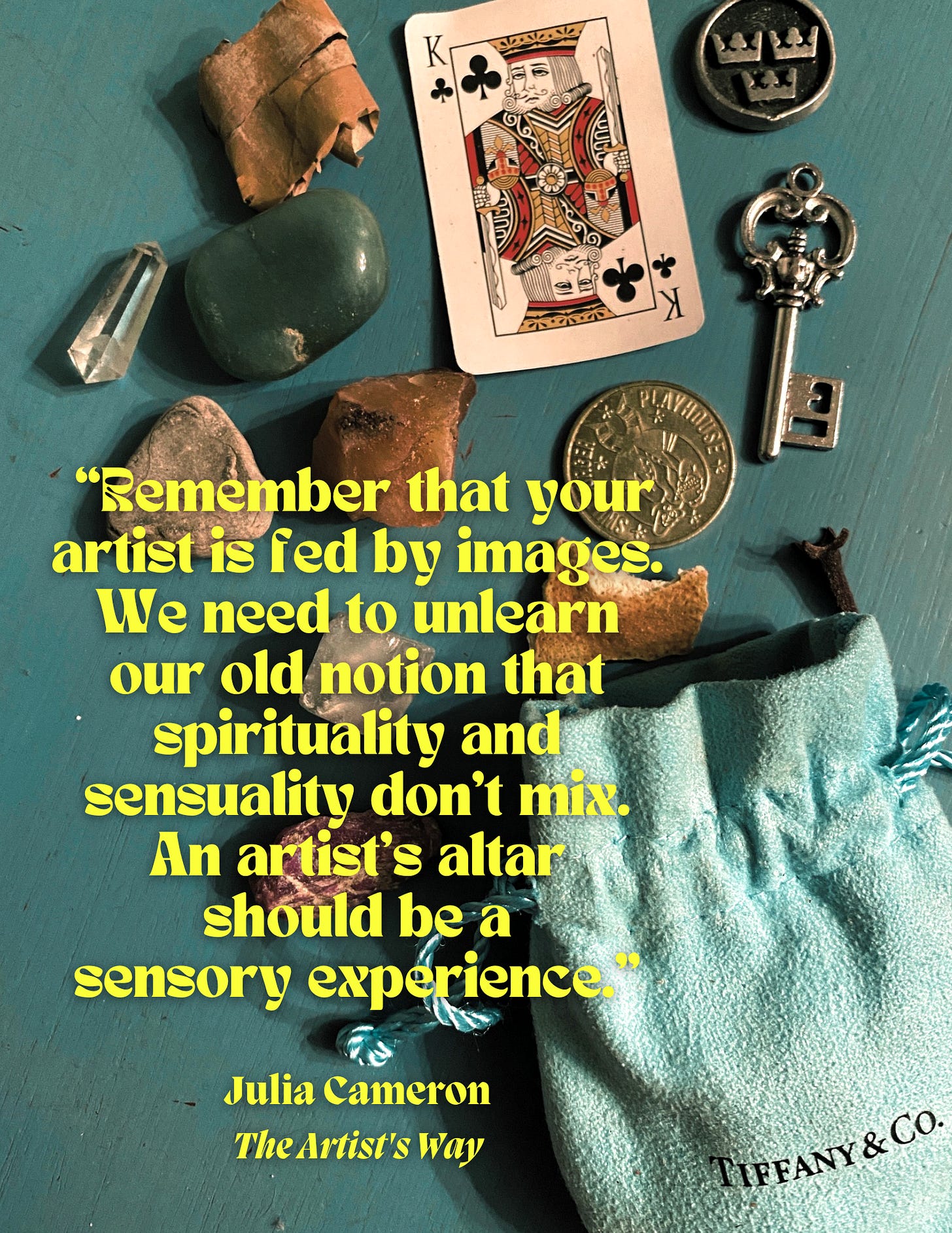Image with the contents of a small Tiffany & Co. sachet on a blue table: an arcade token, a small King of Clubs playing card, crystals, a key, a necklace charm, and a piece of birch bark. Text: "Remember that your artist is fed by images. We need to unlearn our old notion that spirituality and sensuality don't mix. An artist's altar should be a sensory experience.” Julia Cameron, The Artist's Way