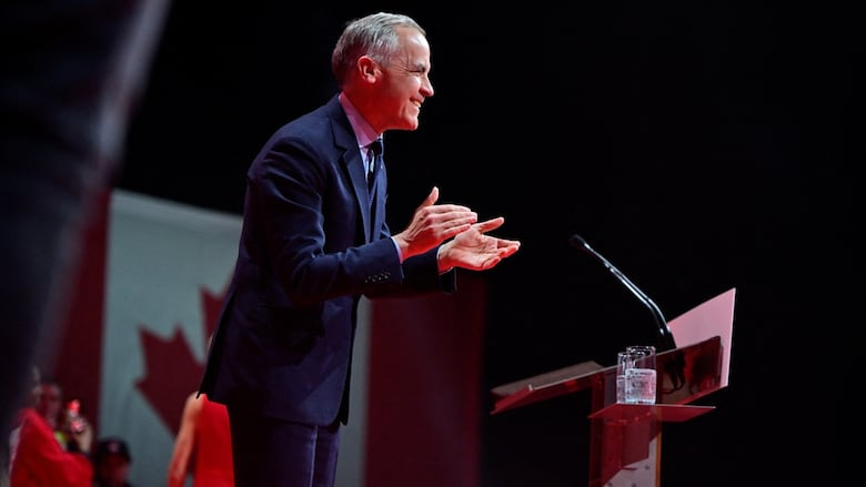 A smiling politician claps on stage.