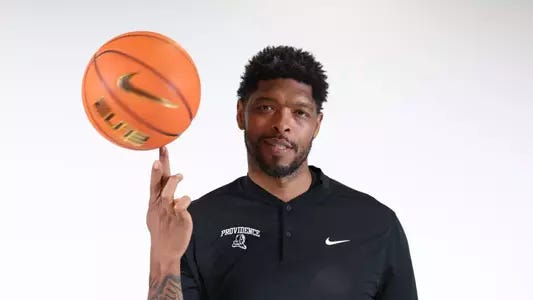 Ryan Gomes, men's basketball assistant coach, posing spinning a basketball on his finger.