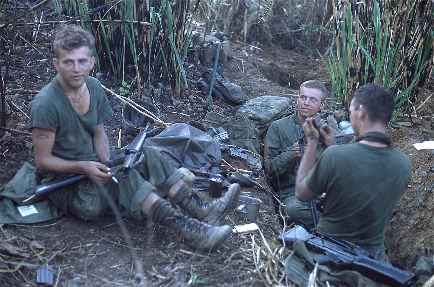 Three Marines from an infantry machine gun team in a dense jungle during the Vietnam War.