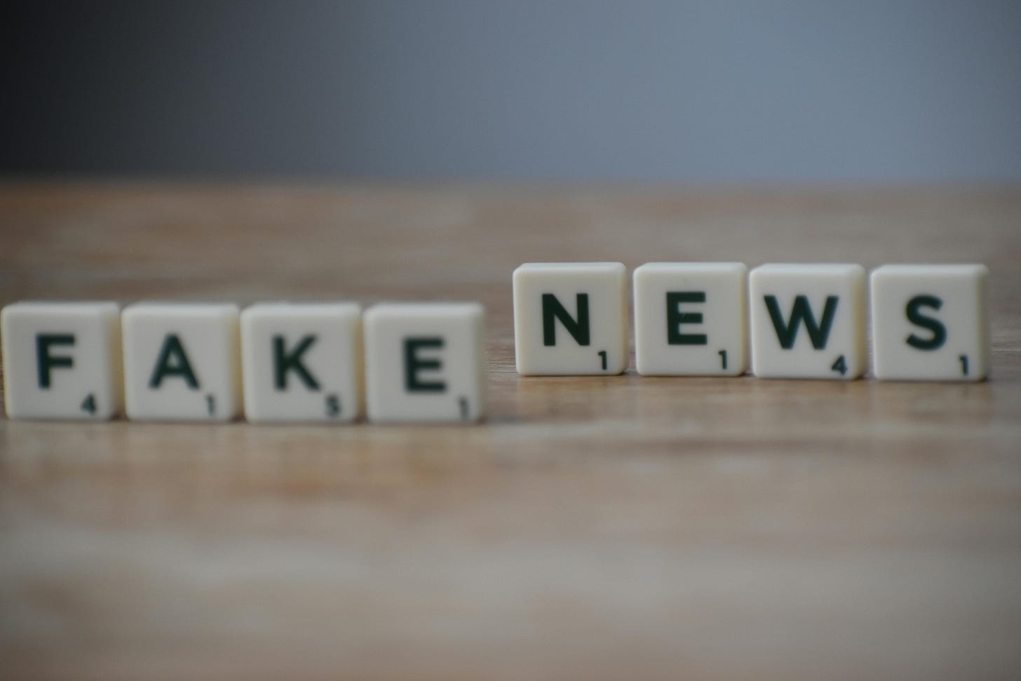 Scrabble tiles on a table that spell out “fake news”