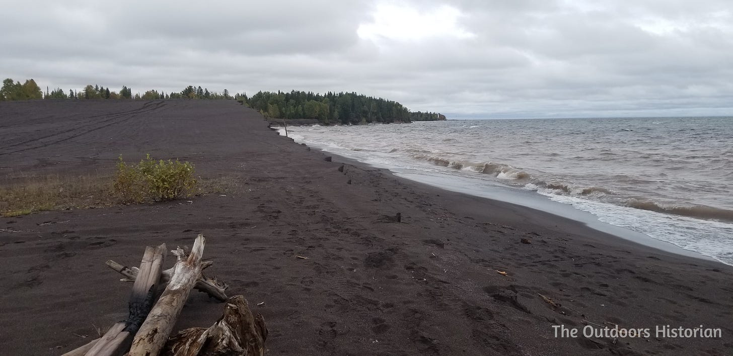 A steep dune of black sands along Lake Superior on a windy, grey day.