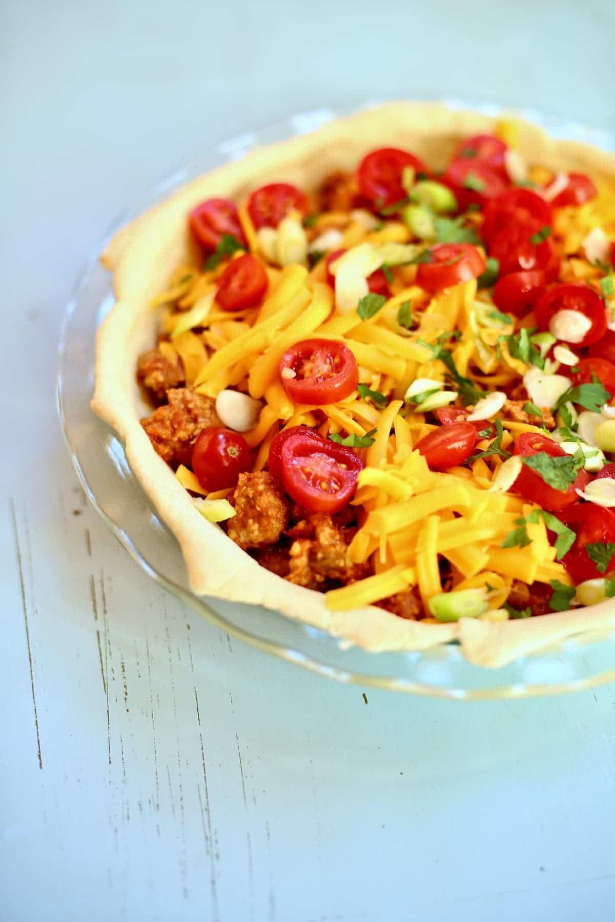 an uncooked taco pie on a blue table.